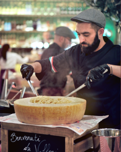 Un membre de la squadra entrain cuisinier dans une meule de parmesan